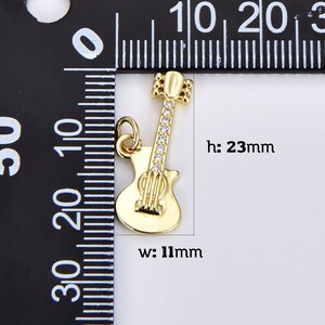 May include: Gold-tone guitar charm with clear rhinestones. The charm is 23 mm high and 11 mm wide.