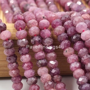 May include: A strand of pink faceted gemstone beads. The beads are round and have a slightly irregular shape. The beads are strung on a clear thread.