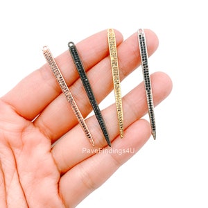 Könnte beinhalten: Vier lange, dünne, spitze Anhänger mit einer Pavé-Fassung aus schwarzen Zirkonia-Steinen. Die Anhänger sind in den Ausführungen Gold, Silber, Roségold und Schwarz erhältlich. PaveFindings4U ist unter den Anhängern gedruckt.