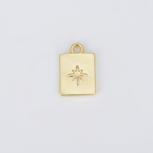 May include: Gold charm with a square shape and a star design. The star is raised and has a slightly textured surface.