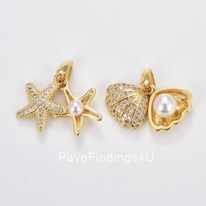 May include: Two gold-tone charms with clear crystal accents. One charm features a starfish with a pearl accent. The other charm features a seashell with a pearl accent. PaveFindings4U.