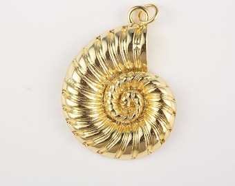 Puede incluir: Un colgante dorado con forma de concha de nautilus. El colgante tiene un diseño en espiral con crestas detalladas y un lazo en la parte superior para una cadena. La concha está muy pulida, reflejando la luz.