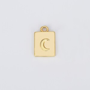 May include: Gold charm with a crescent moon design in a square shape.