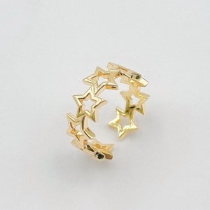 May include: A gold-toned ring with a design of interlocking stars. The ring is open and adjustable.