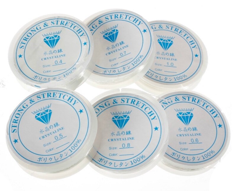 Puede incluir: Seis carretes de hilo el&aacute;stico transparente, cada uno etiquetado con el texto "Strong & Stretchy" y "Crystaline" en japon&eacute;s. Los carretes est&aacute;n etiquetados con diferentes tama&ntilde;os, que van de 0,4 a 1,0.