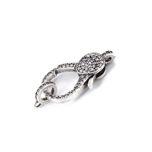 May include: Silver-toned clasp with a round, clear crystal-encrusted design. The clasp is designed to be used for jewelry making.