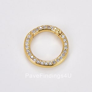 May include: Gold-toned metal circle charm with a pave setting of clear cubic zirconia stones. The charm has a hinged opening.