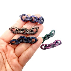 May include: A selection of decorative chain links in shades of purple, brown, blue, green, and pink. Each link is adorned with small, sparkling stones. The links are joined together and have small loops at each end.