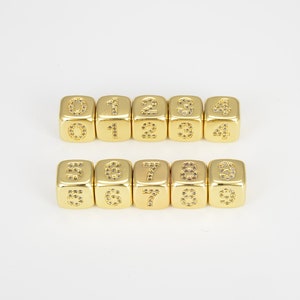 May include: Ten gold dice with numbers 0 through 9, each number is made of small clear rhinestones.