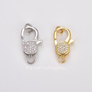 May include: Two silver and gold lobster clasps with clear cubic zirconia stones. The clasps are for jewellery making.