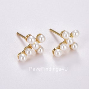 May include: A pair of gold stud earrings with a cluster of small white pearls arranged in a cross shape.