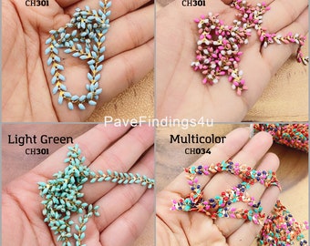 May include: Four different colors of decorative chain trim with gold accents. The colors are light blue, light green, two-tone pink and white, and multicolor. The chain is made of small, leaf-shaped beads.