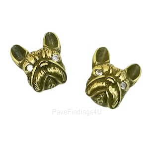 May include: A pair of gold-tone French bulldog earrings with clear crystal accents. The earrings are detailed with a textured finish.