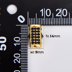May include: Gold-toned spacer bead with black cubic zirconia stones. The bead is 14mm high and 9mm wide. h: 14mm w: 9mm