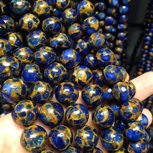 May include: A strand of blue and gold gemstone beads. The beads are round and have a speckled pattern.