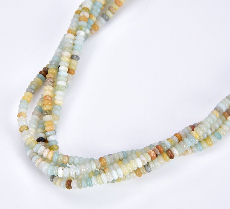 May include: A strand of multi-colored gemstone beads. The beads are a mix of light blue, green, yellow, and brown. The beads are small and round.