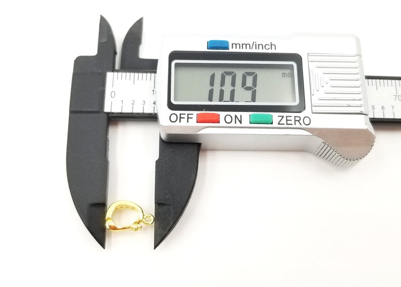 以下が含まれることがあります： デジタルノギスを使用して測定した、金色の金属製留め具は、長さが10.9mmです。留め具は、チェーンやコードを取り付けるために使用される一般的なジュエリーパーツです。