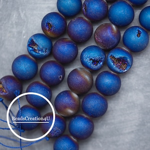 May include: A strand of blue agate beads with iridescent shimmer. The beads have a natural, druzy finish and are strung on a blue cord. The text "BeadsCreation4U" is visible in the image.