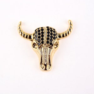 May include: Gold-tone bull skull pendant with black rhinestone accents.