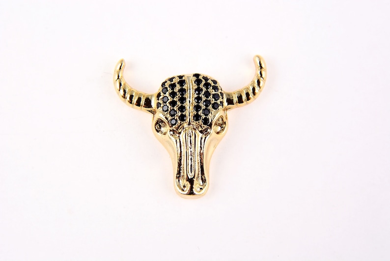 May include: Gold-tone bull skull pendant with black rhinestone accents.