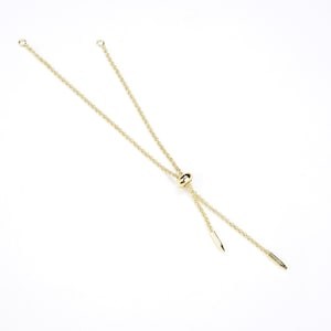 May include: A gold chain bracelet with a sliding clasp. The chain is made of small, round links. The clasp is a small, round bead.