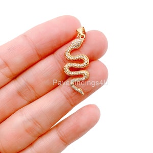 May include: Gold-tone snake pendant with clear cubic zirconia stones. The snake is coiled and has a smooth, polished finish.