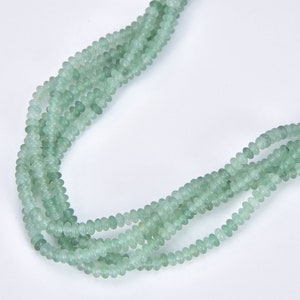 May include: A strand of light green beads, made of natural stone, with a smooth, rounded shape. The beads are strung together on a clear thread.