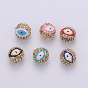 May include: Six gold-toned round beads with an evil eye design. The beads are decorated with clear rhinestones and have different colored enamel eyes: blue, pink, red, black, turquoise, and blue.