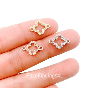 May include: Three clover-shaped connector charms with clear cubic zirconia stones. The charms are available in gold, silver, and rose gold.