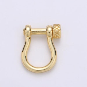 May include: Gold-toned metal clasp with a textured knob. The clasp is shaped like a U with a small bar connecting the two ends.