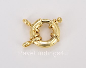 May include: A gold-colored, round toggle clasp with a bar and ring design. The clasp features a circular ring with a bar that inserts into the ring. The bar is attached to the ring with a small loop. The clasp is made of a shiny, gold-toned metal.