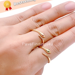 May include: Two gold snake rings with red and green gemstone eyes. The rings are adjustable and can be worn on any finger.
