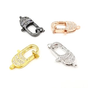 Pu&ograve; includere: Quattro chiusure a moschettone di diversi colori con decorazioni in cristallo trasparente. Le chiusure sono in nero, oro, oro rosa e argento.