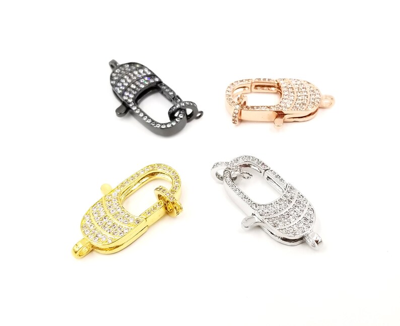 Pu&ograve; includere: Quattro chiusure a moschettone di diversi colori con decorazioni in cristallo trasparente. Le chiusure sono in nero, oro, oro rosa e argento.