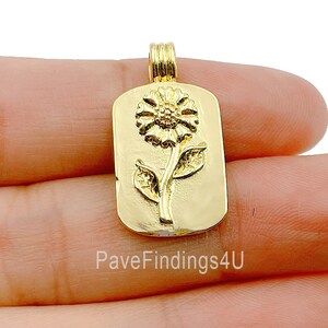May include: Gold-toned pendant charm featuring a raised sunflower design. The charm is rectangular in shape with a smooth, polished finish.