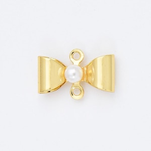 May include: Gold-tone bow-shaped clasp with a single white pearl in the centre. The clasp has two loops on either side for attaching jewellery.