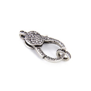 May include: Silver-toned clasp with a round, clear crystal-encrusted top. The clasp is designed for jewelry making.
