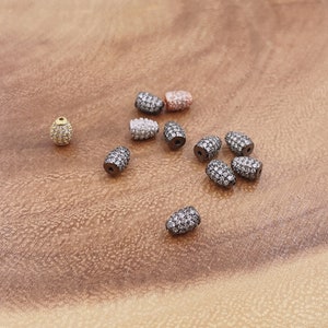 May include: Assortment of small, oval-shaped beads with a pave setting of clear rhinestones. The beads are in various metal finishes, including gold, silver, and black.