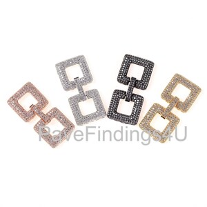 Può includere: Quattro ciondoli connettore a forma quadrata con una pavé di strass trasparenti. I ciondoli sono disponibili in quattro diverse finiture metalliche: argento, oro, oro rosa e nero.