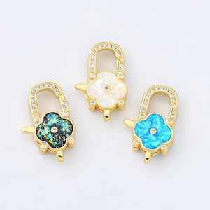 May include: Three gold-toned flower-shaped clasps with clear rhinestone accents. The clasps are decorated with iridescent enamel in shades of blue, green, and white.