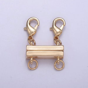 May include: Gold-colored magnetic clasp with two lobster claw clasps and two small rings. The clasp is rectangular with a magnetic closure. Ideal for jewelry making, this clasp provides a secure and stylish way to fasten necklaces or bracelets.