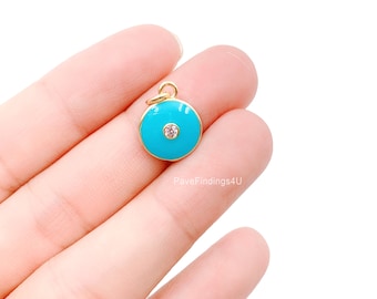 Puede incluir: Encanto de oro con un círculo de esmalte azul turquesa y un pequeño strass transparente en el centro.