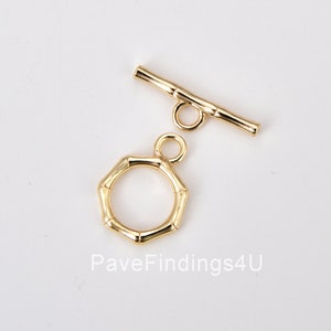 May include: Gold-toned metal toggle clasp with a round, bamboo-style ring. The clasp is made of two pieces: a bar with a loop on one end and a round ring with a loop on the other end.