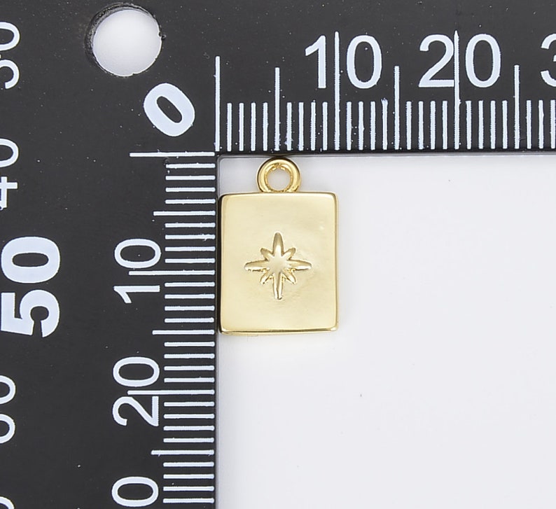 May include: Gold-toned charm with a star design. The charm is square shaped and measures approximately 1 cm in width.