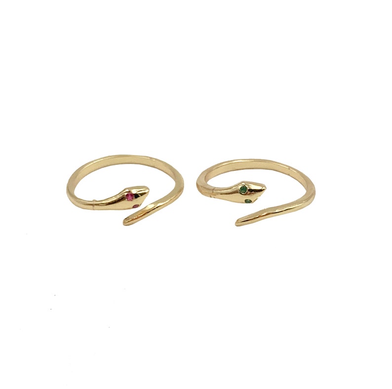 May include: Two gold snake rings with a single red and green gemstone on each. The rings are open and adjustable.
