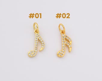 Pode incluir: Dois pingentes de nota musical dourados com detalhes em cristal transparente. Os pingentes são etiquetados como #01 e #02.