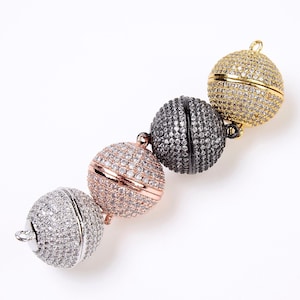 May include: Four magnetic clasps for jewelry making. The clasps are round and covered in clear rhinestones. The clasps are in gold, rose gold, black, and silver.