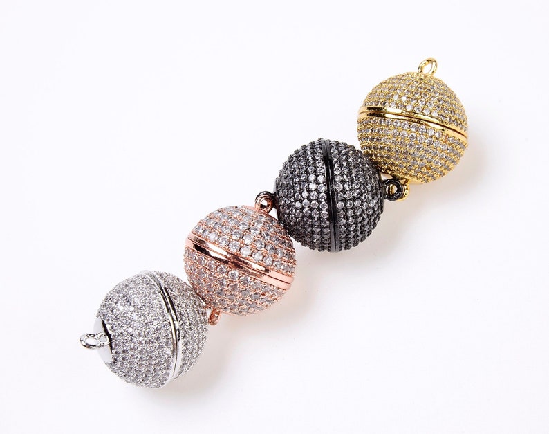 May include: Four magnetic clasps for jewelry making. The clasps are round and covered in clear rhinestones. The clasps are in gold, rose gold, black, and silver.