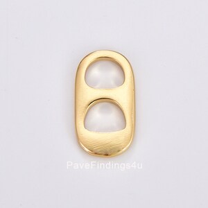 May include: A gold-colored, oval-shaped jewelry finding with two circular openings. The finding has a smooth, polished surface and is designed for jewelry making. The text "PaveFindings4u" is visible at the bottom of the image.