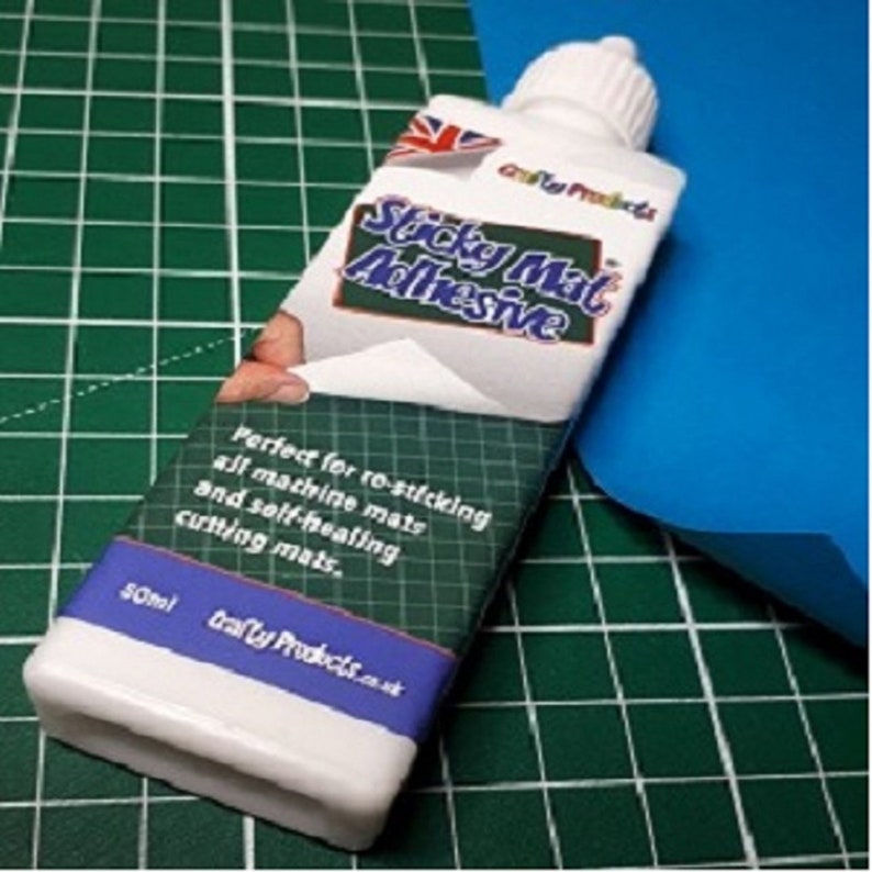 May include: A white bottle of sticky mat adhesive with a green and white label. The label says "Sticky Mat Adhesive" and "Perfect for re-sticking all machine mats and self-healing cutting mats." The bottle is 50 ml.